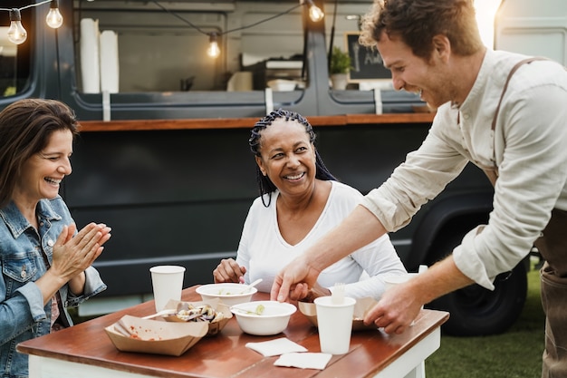 Donne multirazziali che mangiano al ristorante del camion di cibo all'aperto - focus sul volto di donna africanaafrican