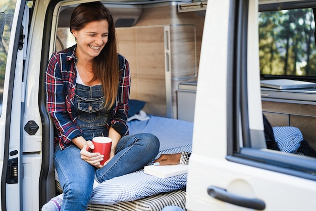 Amici di donne multirazziali che si divertono in campeggio all'interno del camper all'aperto nella foresta di montagna focus sul volto femminile sinistro