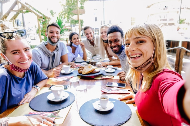 Multiraciale groep vrienden die beschermingsmasker dragen in het restaurant