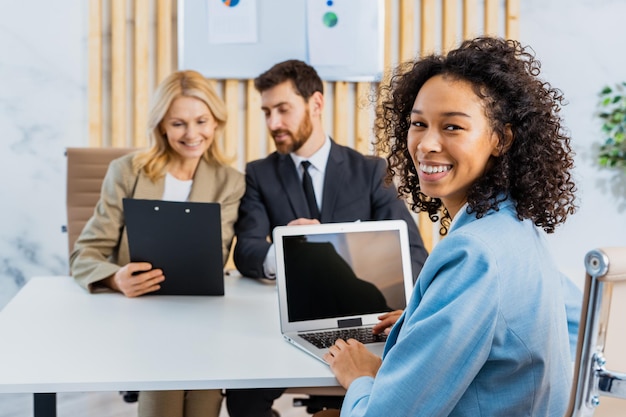 Multiraciale groep zakenmensen met elegante jurk die aan een computerbureau op kantoor zit