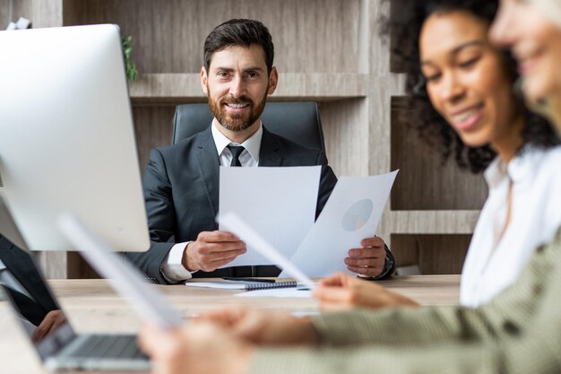 Multiraciale groep zakenmensen met elegante jurk die aan een computerbureau op kantoor zit