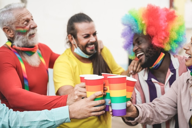 Foto multiraciale homo's juichen met regenboogglazen tijdens pride-parade buiten tijdens uitbraak van coronavirus - focus op bril