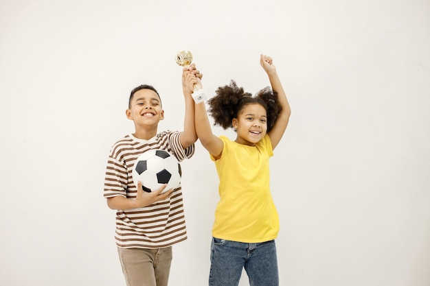 Multiraciale jongen en meisje hand in hand met winnaar cup