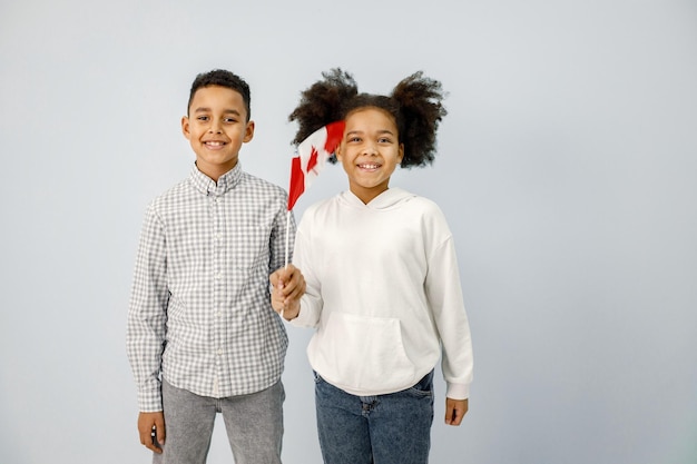 Multiraciale jongen en meisje staan geïsoleerd op een blauwe achtergrond en houden een vlag van canada vast