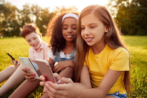 Multiraciale kinderen die gadgets gebruiken in het park