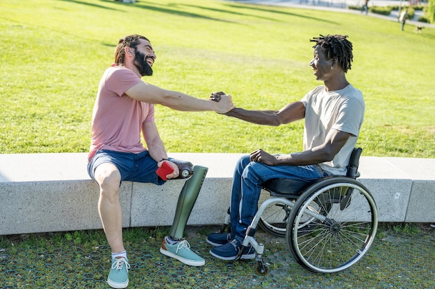 Multiraciale mensen begroeten elkaar gelukkige vrienden met een handicap die plezier hebben in parkstad