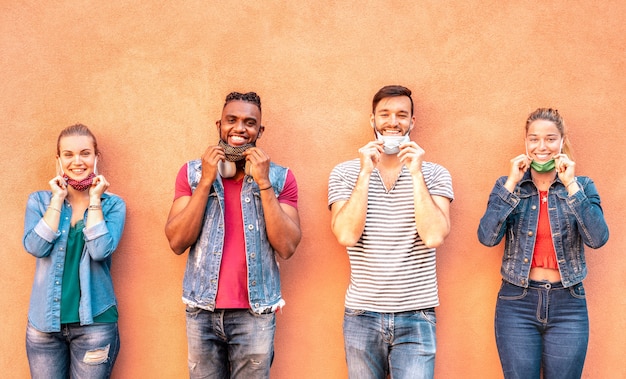 Multiraciale millennialvrienden die met gezichtsmasker glimlachen na heropening van lockdown