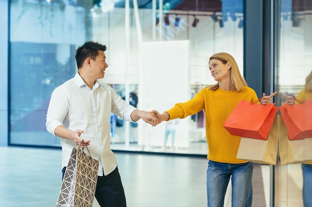 Foto multiraciale paar aziatische man en blanke vrouw lopen samen in het winkelcentrum na het winkelen met