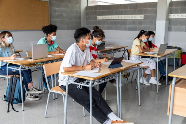 Multiraciale tiener middelbare scholieren in de klas dragen beschermende gezichtsmaskers Onderwijs Gezondheidszorg