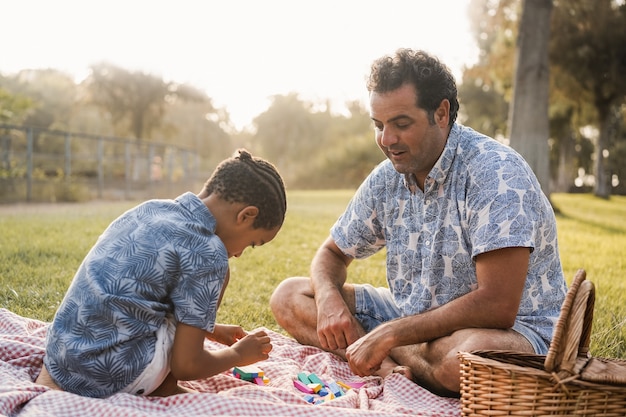 Multiraciale vader en zoon hebben plezier met houten speelgoed buiten in het stadspark - Focus op papa's gezicht