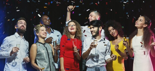 Multiraciale vrienden dansen op nieuwjaarsfeest op donkere achtergrond