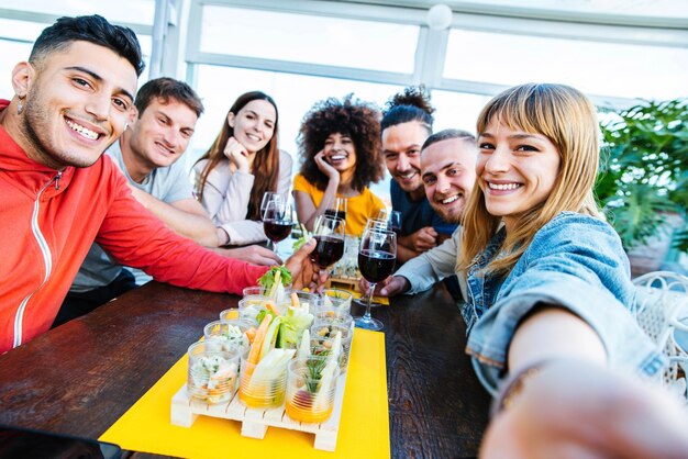 Multiraciale vrienden die een selfie maken en wijnglazen toejuichen aan de bar