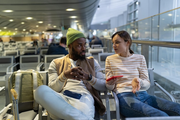 Multiraciale vrienden praten en bespreken reisplan tijdens het wachten op de vlucht in de luchthavenlounge