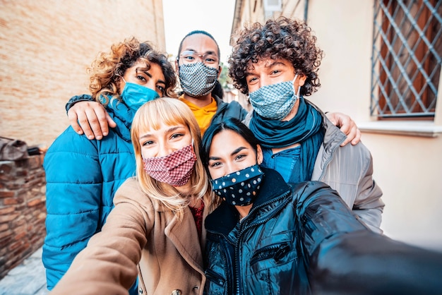 Foto multiraciale vrienden vallende gezichtsmasker nemen selfie winterkleren dragen