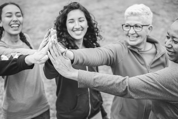 Foto multiraciale vrouwen stapelen handen buiten in stadspark - hoofdfocus op afrikaanse vrouwelijke hand