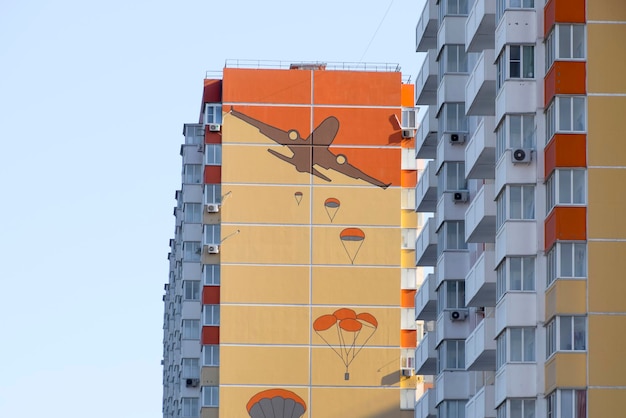 A multistorey house with a painted wall Figure depicting the landing of paratroopers from an airplane