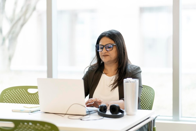 Photo multitasking asian mature business woman working online on laptop in modern office interior