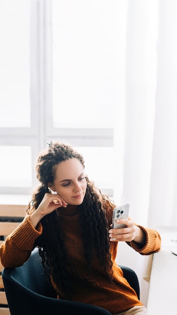 Multitasking jonge vrouw die smartphone en laptop gebruikt voor werken op afstand en e-learning vanuit huis