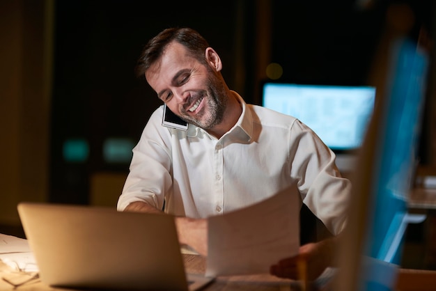 Multitasking man die laat op kantoor werkt