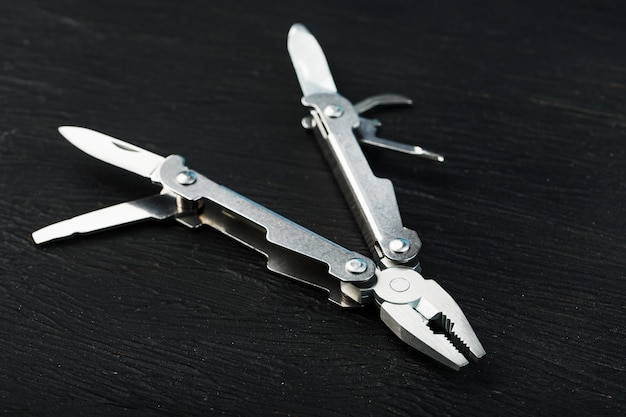 Multitool is a multi-functional tool on a black background. The concept of an expanded multi-tool with free space.