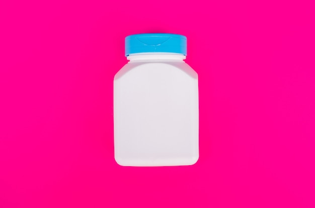ピンクの背景、ビタミンのマルチビタミン瓶の白い色。