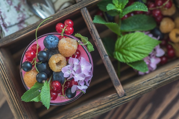 Multivitamine zomerbes heerlijke panacotta Zoet eten met frambozen bosbessen aalbessen croutons en mint roze hortensia boeket donkere houten achtergrond bovenaanzicht