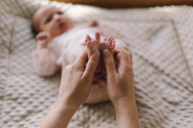 Mum making baby massage mother massaging infant bare foot preventive massage for newborn mommy stroking the baby's feet with both hands Love baby Newborn baby and mother