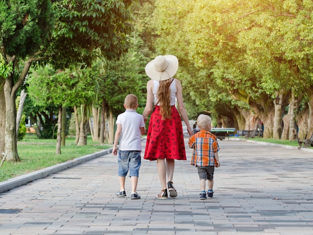 Mum and two sons walking in the park, sunny day.