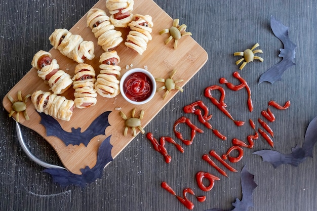 Mummie worstjes op een snijplank met ketchup en olijven spinnen