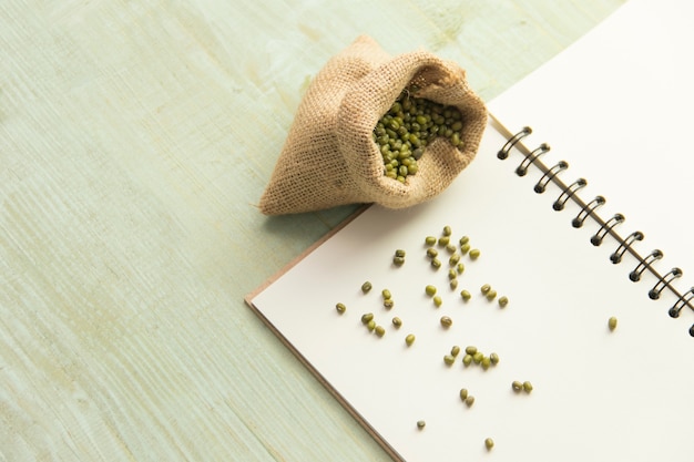 Mung bean and blank notepad on wooden table