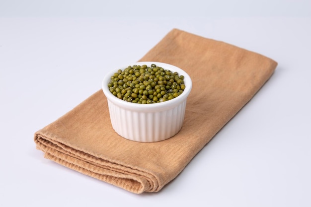 Foto fagiolo verde in una ciotola bianca su un panno e uno sfondo bianco girato in studio