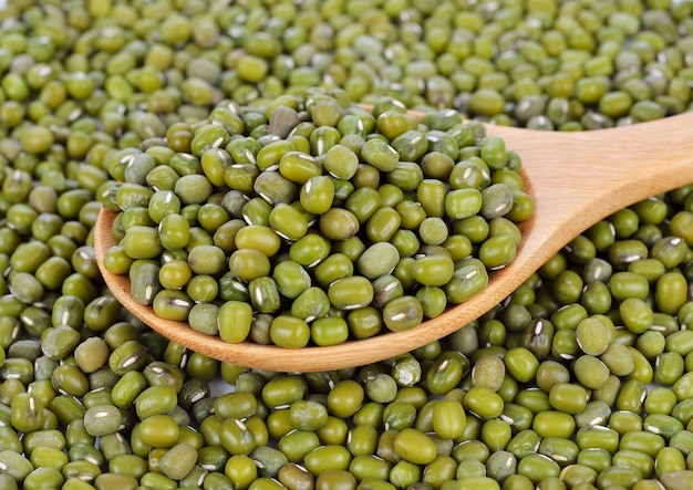 Mung beans in wooden spoon on mung beans background.