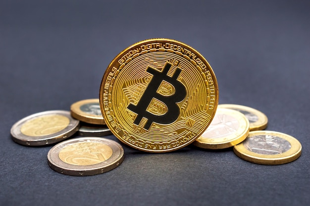 Munt van bitcoin en hoop euromunten op zwart