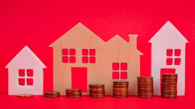 Munten en huizen op een rode achtergrond Het concept van de stijgende prijs van onroerend goed