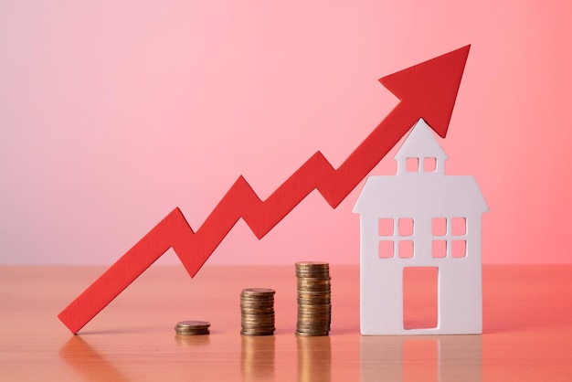 Munten op een tafel een rode pijl omhoog en huisvest het concept van de stijgende prijs van onroerend goed