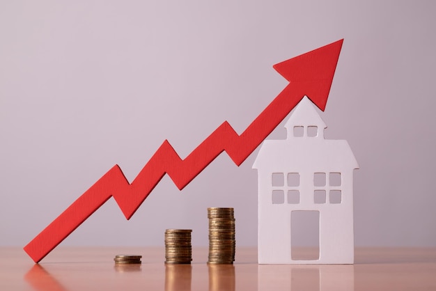 Munten op een tafel een rode pijl omhoog en huisvest het concept van de stijgende prijs van onroerend goed