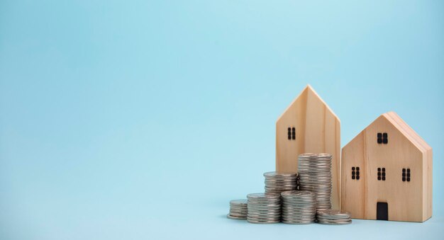 Munten stapelen voor houten huis op houten tafel, geld besparen concept, investeringen in onroerend goed, huis lening, omgekeerde hypotheek, gouden munten geld stapel groei, geld besparen munten stapelen toekomst voor thuis