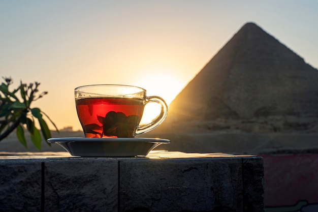 Muntthee drinken in een café terwijl je de indrukwekkende drie piramides van Gizeh aanschouwt. Transparante glazen mok met zwarte thee en munt op de achtergrond van de Egyptische piramides.