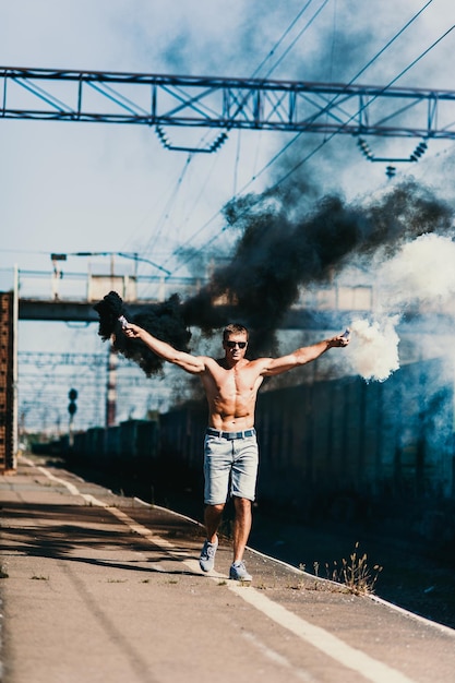 Muscled man holding smoke bombs in his hands