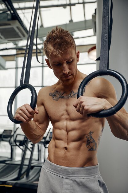 Muscleup oefening jonge man doet intense cross-fit training in de sportschool op gymnastiekringen