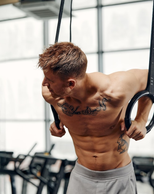 Muscleup oefening jonge man doet intense cross-fit training in de sportschool op gymnastiekringen