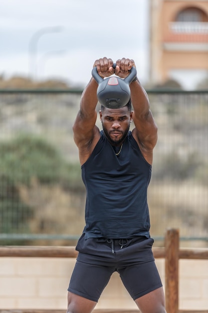 Musculaire sportman doet kettlebell swing oefening in het park