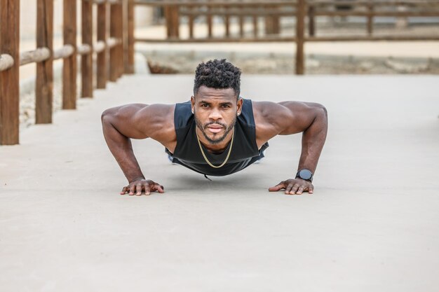 Musculaire zwarte atleet die push-ups doet.