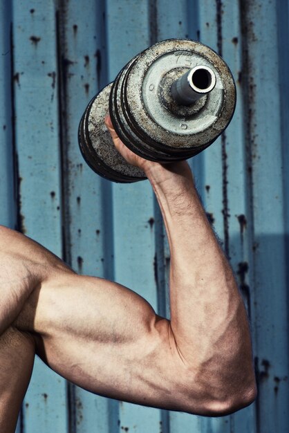 Photo muscular arm with dumbbell close up