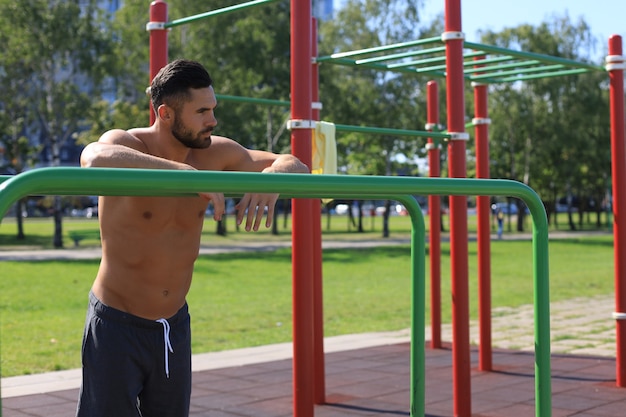 Photo muscular athlete relaxing after intense workout outdoors.