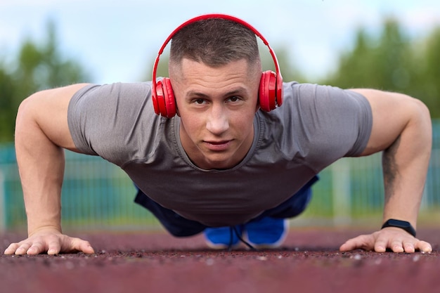 Muscular athlete in a Tshirt and shorts does a pushup exercise