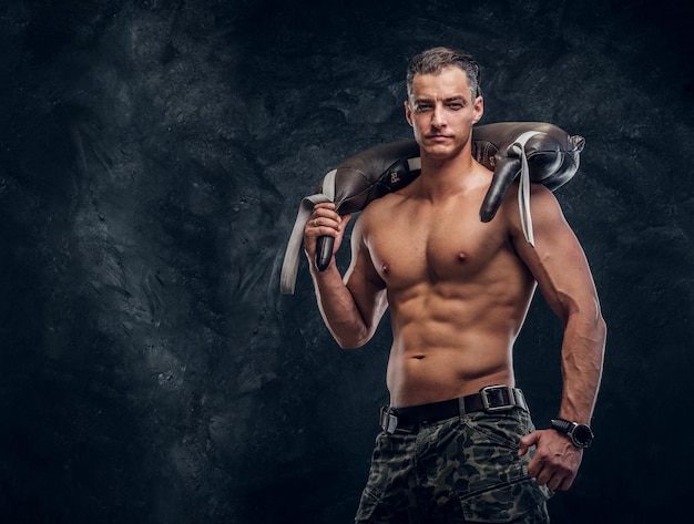 Muscular attractive hot man is holding weight bag while posing for photographer.