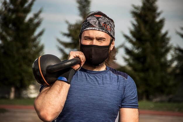 Photo muscular bearded male athlete workout outdoor with kettlebell we