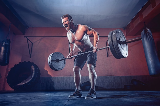 Muscular beardedman working out in gym doing exercises, strong male naked torso abs.