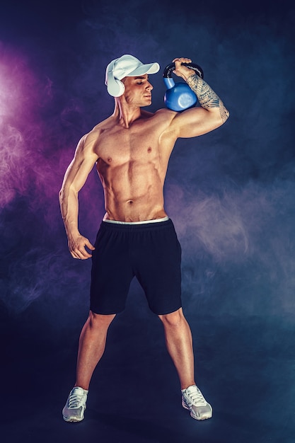 Muscular bodybuilder doing Exercise with kettlebell.  shot with smoke.